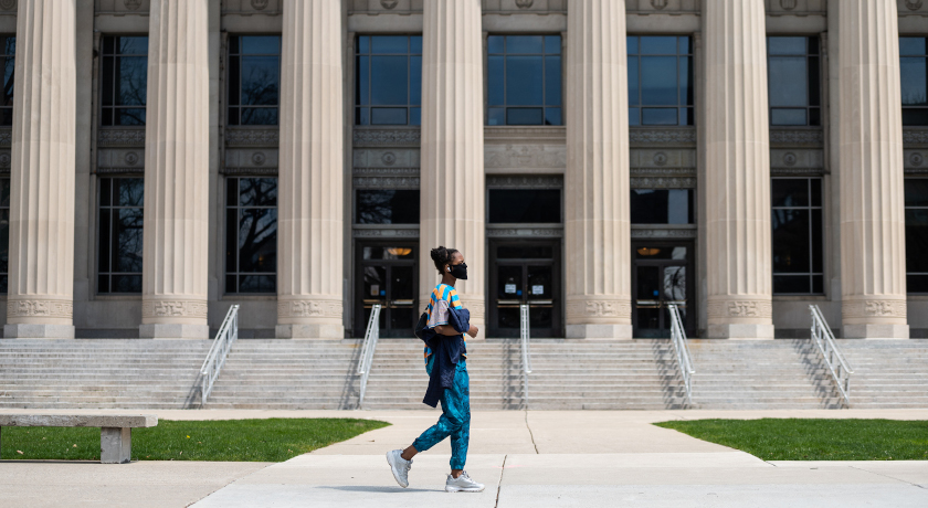 A student walking near Angell Hall, located on the Ann Arbor campus