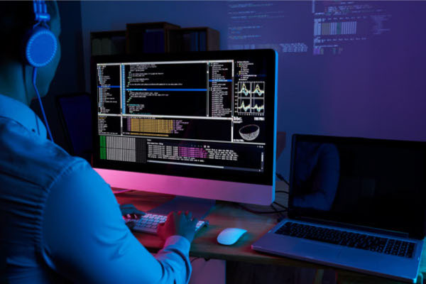 A person writing code on a computer in dark mode with visualizations