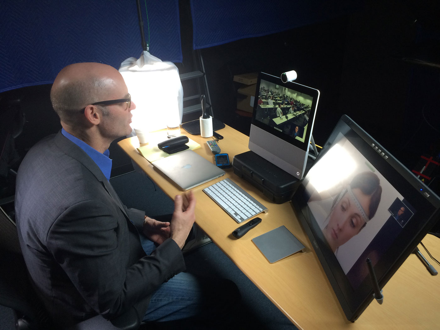 A professor lecturing remotely to a hall filled with students