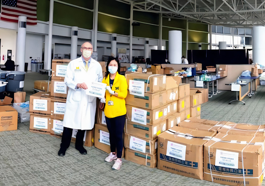 Michigan Medicine staff stand in front of multiple boxes of donated Personal Protective Equipment